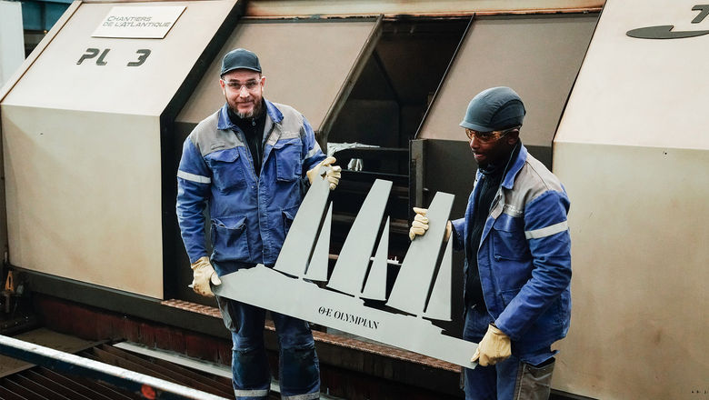 At the keel laying ceremony for the Orient Express Corinthian, shipbuilders Younoussa Diallo and Eddy Lairet hold up a steel cutout of the ship.